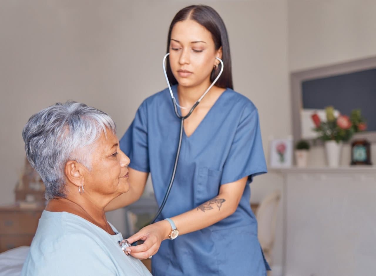 Nurse listening to an elderly patient's heartbeat with a stethoscope