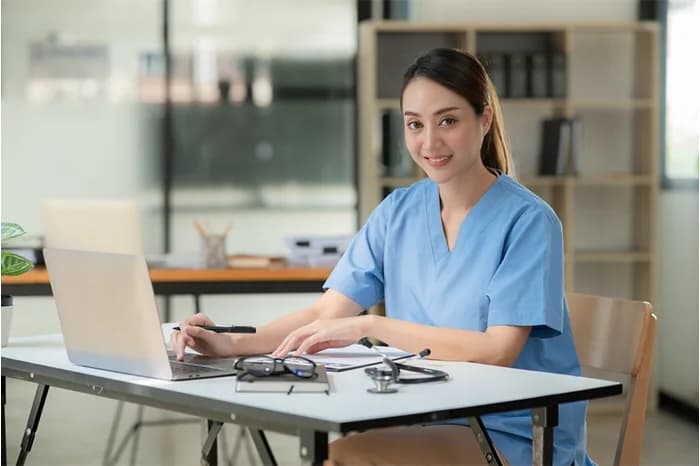 Registered nurse in blue scrubs working at a desk