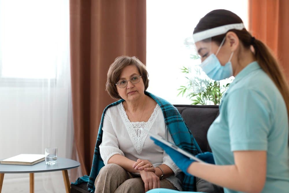 Personal support worker in a face shield and mask talking with a client